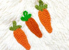 three crocheted carrots sitting on top of a white furnishing area