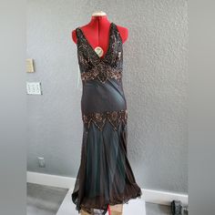 a mannequin is dressed up in a black and brown dress with gold accents