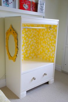 a white cabinet with yellow flowers painted on the front and bottom, sitting in a bedroom