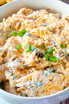 a close up of a bowl of food with cheese and green garnish on top