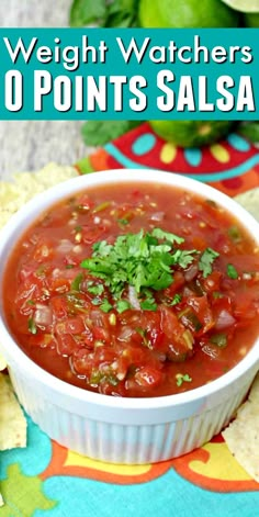 a white bowl filled with salsa next to tortilla chips and cilantro