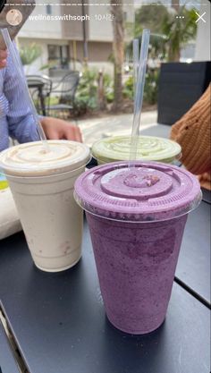 two drinks sitting on top of a table with straws in each cup and one is purple