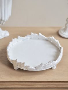 a white plate sitting on top of a wooden table next to two candlesticks