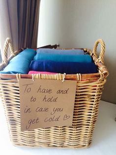 a wicker basket with blue pillows and a sign that says to have and to hold in case you get cold