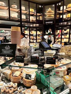 people are shopping in a store with cheeses and other items on the shelves behind them