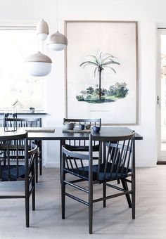 a dining room table with four chairs and a painting hanging on the wall behind it