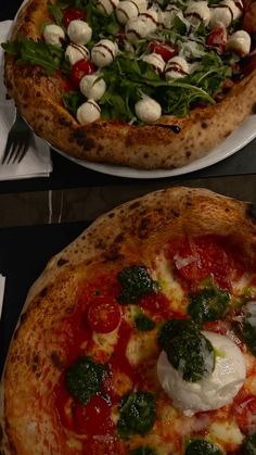 two pizzas with different toppings sitting on top of each other, one topped with cheese and spinach