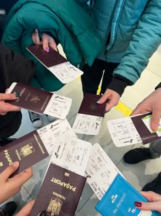 several people are holding their passport in the middle of a circle, with one person pointing at them