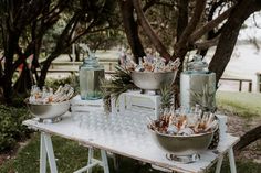 there are many glasses and bottles on the table with food in bowls next to them