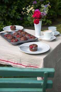 a table topped with cupcakes and muffins next to a vase of flowers