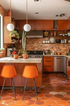 two orange chairs are in the middle of a kitchen with tile flooring and wooden cabinets