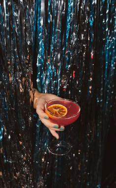 a person holding a wine glass with an orange in it