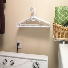 a washer and dryer in a bathroom next to a basket with towels on it