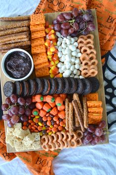 a platter filled with crackers, pretzels, grapes, and other snacks