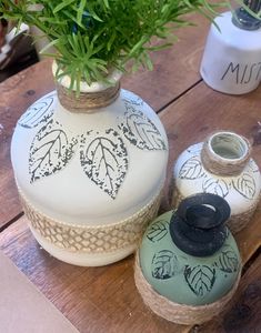 two vases with plants in them sitting on a wooden table next to other items