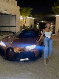 a woman standing next to a brown sports car