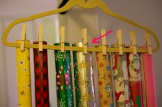 several different colored umbrellas hanging from a wooden hanger with clothes pins attached to them