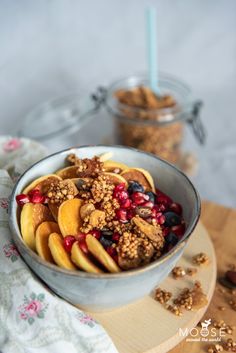 a bowl filled with granola and fruit on top of a wooden cutting board