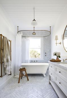 a white bathroom with a tub, sink and mirror on the wall in front of it