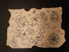 a piece of paper with drawings on it and a compass in front of the map