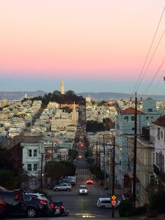 cars are parked on the street in front of a cityscape at sunset or dawn