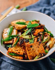 a white bowl filled with tofu and green beans on top of a blue towel