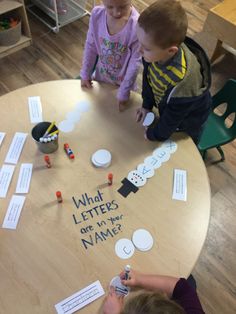 two young children sitting at a table playing with letters and magnets that spell out what letters are in their name