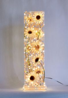 a lighted lamp with daisies and lights on the bottom is in front of a white background