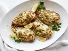 three pieces of chicken on a plate with lemons and parsley