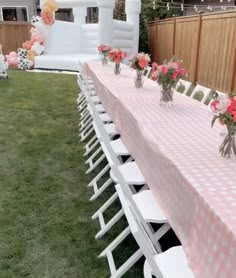 a long table with pink and white flowers in vases sitting on top of it