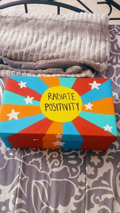 a box with the words radiate positivity on it sitting on a bed