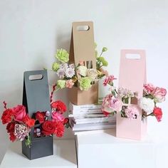 three boxes with flowers in them sitting on top of a white table next to each other