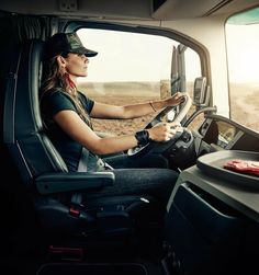 a woman driving a truck in the middle of an open desert area with her hands on the steering wheel