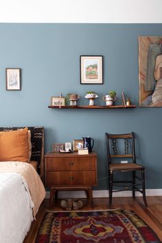 a bed room with a neatly made bed and a painting on the wall above it