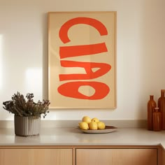 a bowl of lemons sitting on top of a kitchen counter next to a painting