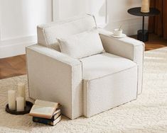 a white chair sitting on top of a rug next to a book and candle holder