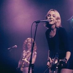 two women singing into microphones on stage