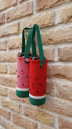 two crocheted watermelon bags hanging on a brick wall