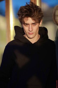 a young man wearing a black hoodie looking at the camera