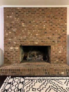 a brick fireplace in a living room with a rug on the floor