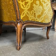 an upholstered arm chair with gold fabric