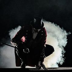 a man in a top hat and coat kneeling down