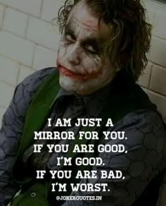 the joker is sitting against a wall with his face painted white and has words written on it