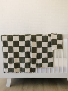 a white crib with a black and white checkerboard blanket on top of it