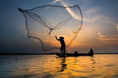 a man standing on top of a boat holding a net