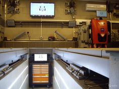 an industrial kitchen with two televisions on the wall and other appliances in the back