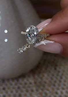 a woman's hand holding an engagement ring with diamonds on the middle and sides