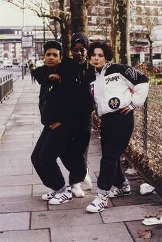 three young men standing next to each other on a sidewalk