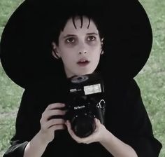 a woman in a black hat holding a camera