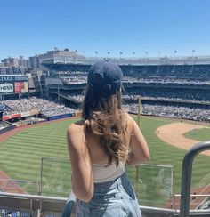 a woman sitting in the bleachers at a baseball game looking out into the stands